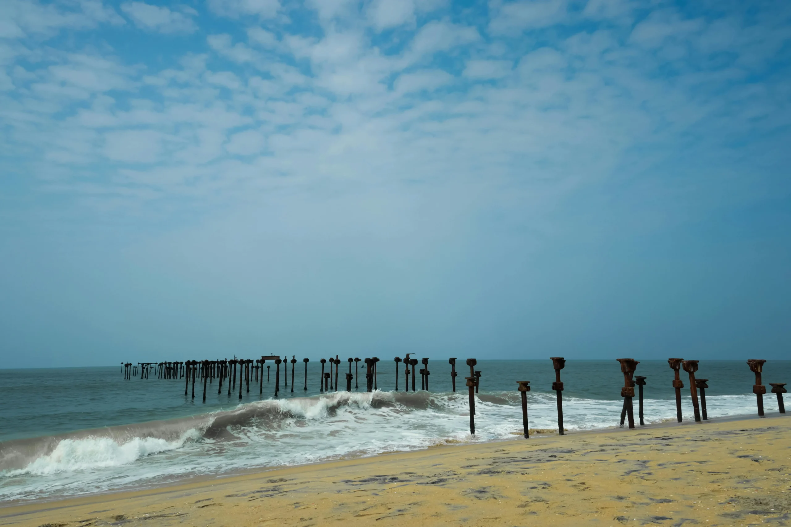 Old pier poles by the beach in Alleppey, a peaceful spot often seen in an Alleppey travel package.